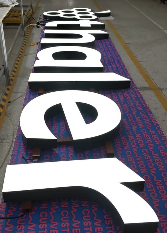 Große weiße Leuchtbuchstaben auf blauer Folie vor der Montage.