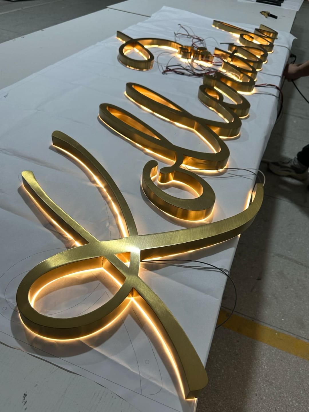 Goldene Schreibschrift-Buchstaben mit rückseitigem Licht.